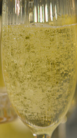 Vertical-Video-Close-Up-Of-Bubbles-As-Person-Pours-Champagne-Into-Glass-At-Vertical-Video-Of-Table